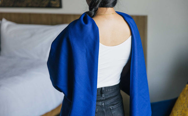 A Large Shepherd's Wool Utility Cloth in Neela Blue being worn as an open-back shawl.